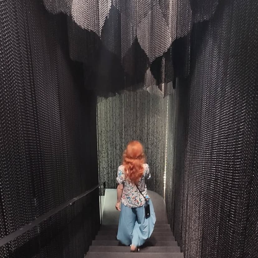 A young woman standing in a room full of lights and mirrors